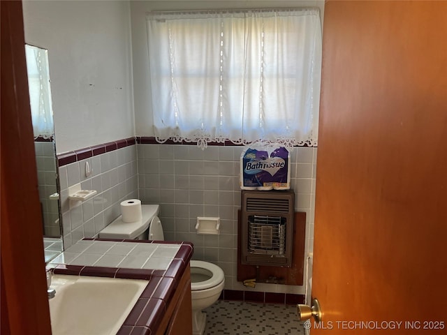 bathroom with vanity, tile patterned floors, toilet, tile walls, and heating unit