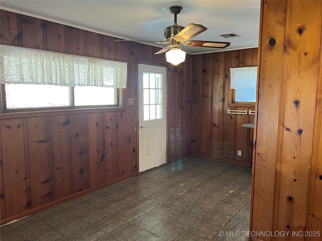 entryway with ceiling fan and wood walls