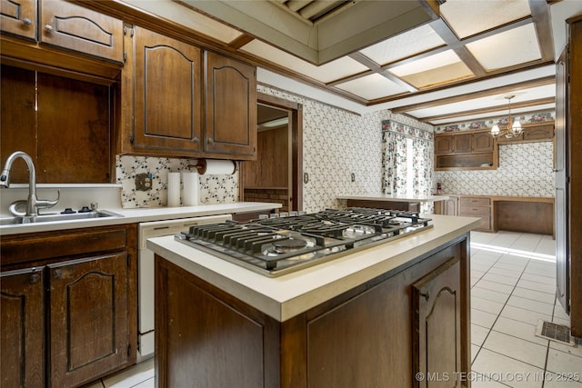 kitchen featuring sink, hanging light fixtures, a kitchen island, stainless steel gas stovetop, and light tile patterned floors