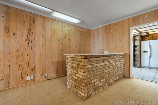 bar with wooden walls, carpet, white refrigerator with ice dispenser, and ornamental molding