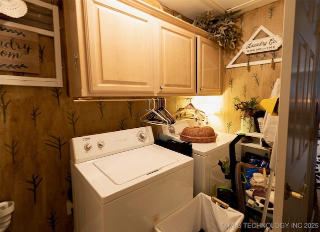 clothes washing area featuring cabinets and washer and dryer