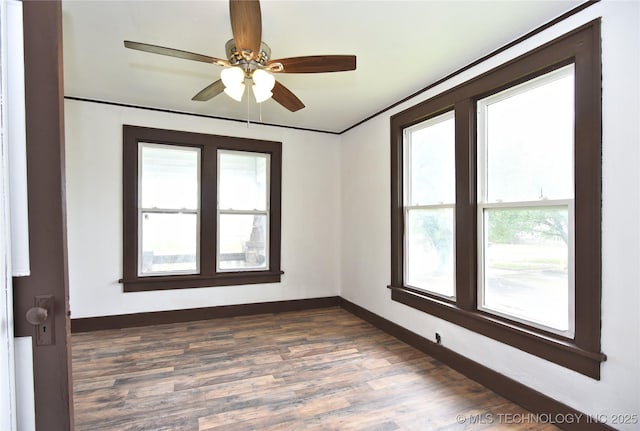 unfurnished room with ornamental molding, ceiling fan, and dark wood-type flooring