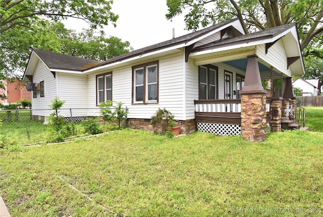 view of side of property featuring covered porch and a yard