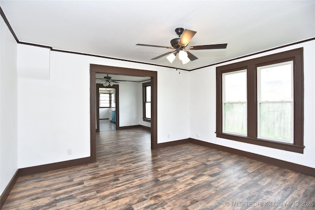 empty room with ornamental molding, ceiling fan, and dark wood-type flooring