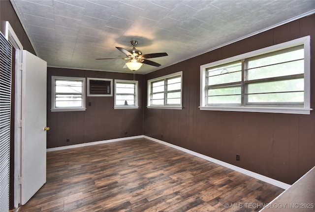 unfurnished room featuring ceiling fan, wood walls, dark hardwood / wood-style floors, and ornamental molding