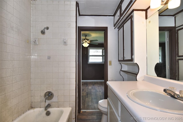 full bathroom with ceiling fan, tiled shower / bath combo, wood-type flooring, toilet, and vanity