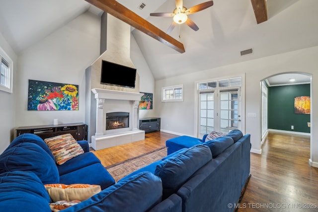 living room featuring ceiling fan, a tile fireplace, beam ceiling, wood-type flooring, and high vaulted ceiling