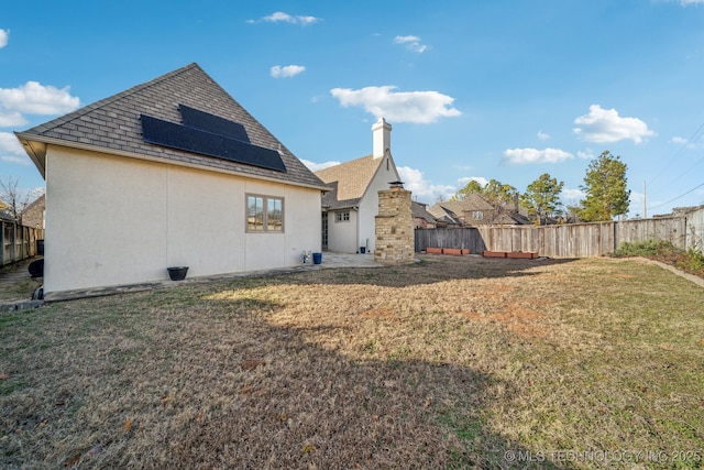 rear view of house featuring a lawn and solar panels