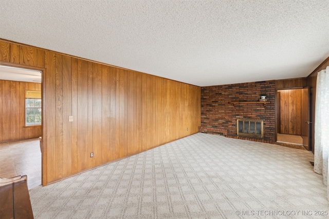 unfurnished living room with wood walls, a fireplace, light colored carpet, and a textured ceiling