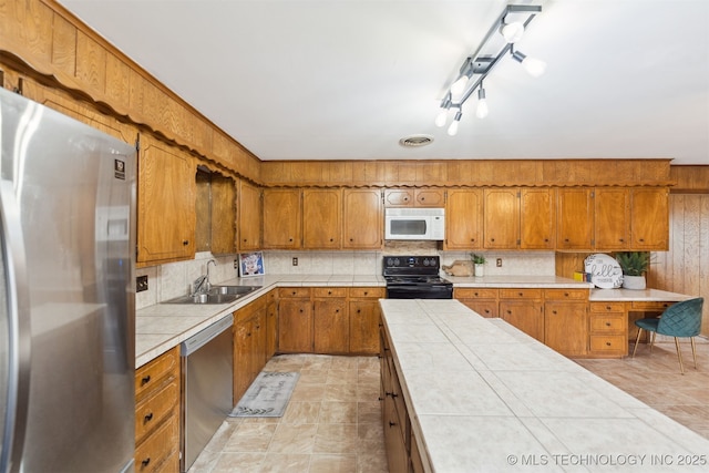 kitchen featuring backsplash, tile counters, sink, and appliances with stainless steel finishes