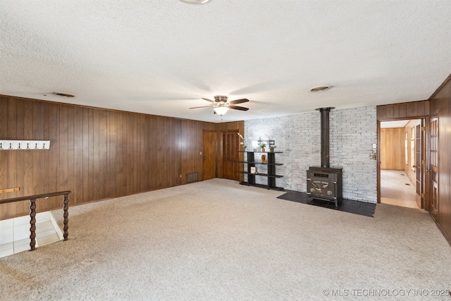 interior space featuring a textured ceiling, a wood stove, and wooden walls