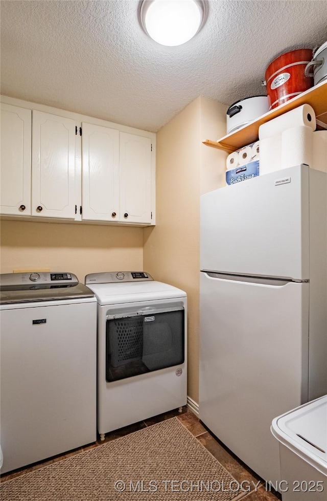 washroom with tile patterned flooring, a textured ceiling, cabinets, and washing machine and clothes dryer