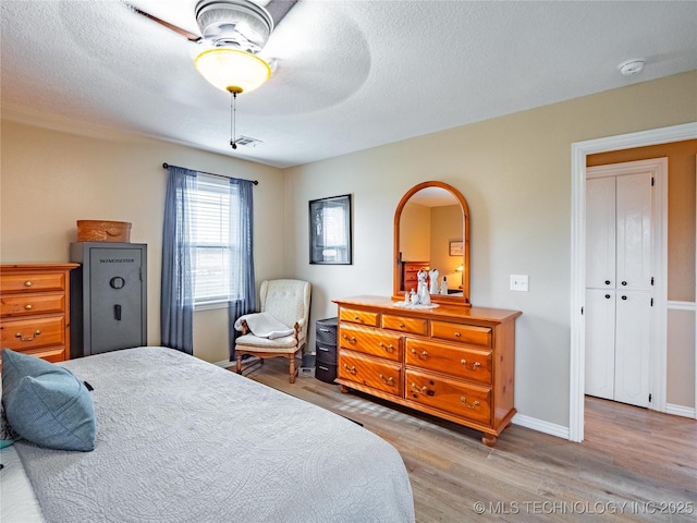 bedroom featuring ceiling fan, wood-type flooring, a closet, and a textured ceiling