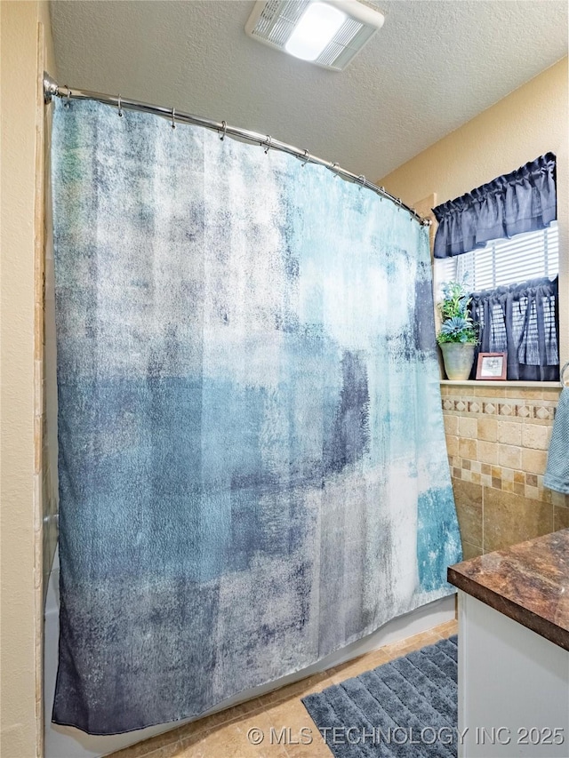 bathroom featuring tile patterned flooring, vanity, and a textured ceiling