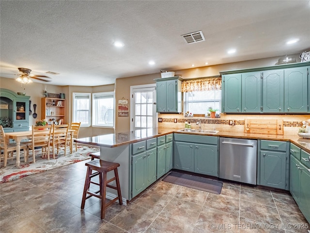 kitchen featuring sink, tasteful backsplash, a kitchen bar, stainless steel dishwasher, and kitchen peninsula