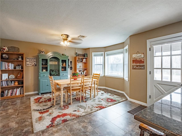 dining area featuring ceiling fan and a textured ceiling