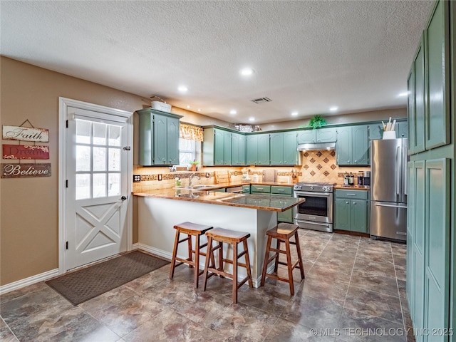 kitchen featuring sink, high quality appliances, a kitchen bar, decorative backsplash, and kitchen peninsula