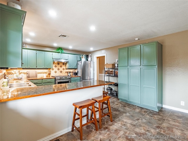 kitchen featuring sink, backsplash, a kitchen breakfast bar, premium appliances, and kitchen peninsula