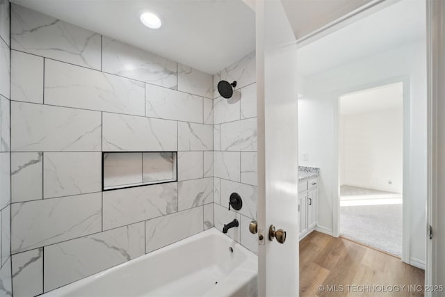 bathroom with hardwood / wood-style floors, vanity, and tiled shower / bath