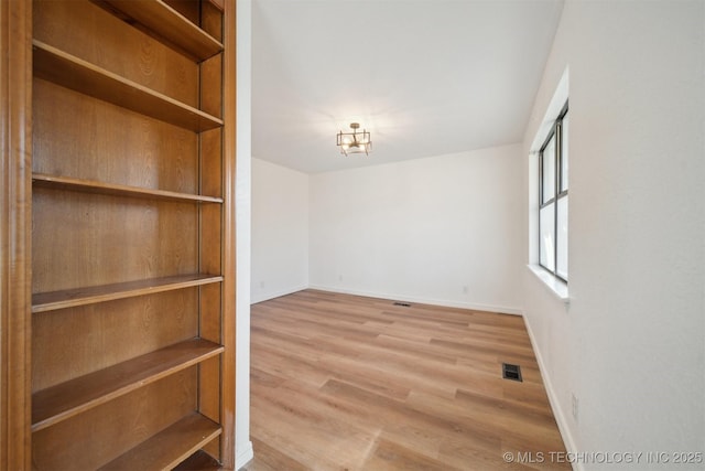 spare room featuring light hardwood / wood-style floors and an inviting chandelier