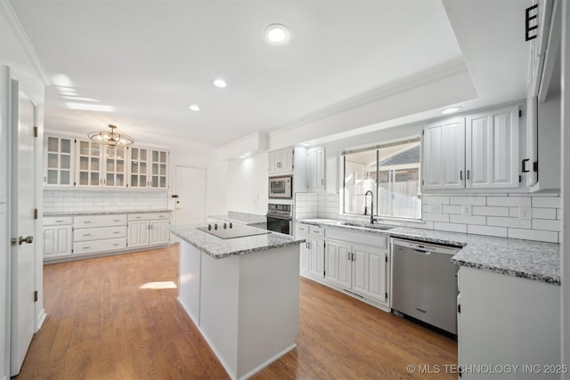 kitchen featuring sink, a kitchen island, light hardwood / wood-style floors, white cabinets, and appliances with stainless steel finishes