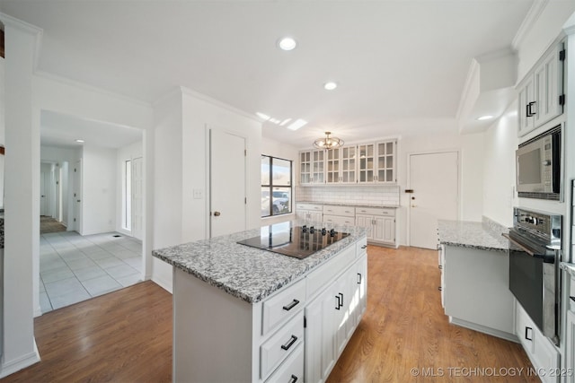 kitchen featuring a center island, backsplash, white cabinetry, and black appliances