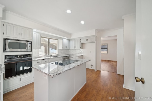 kitchen with a center island, sink, white cabinets, black appliances, and hardwood / wood-style flooring