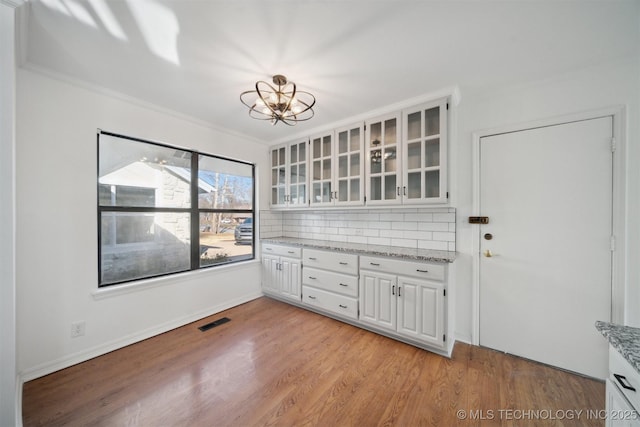 unfurnished dining area with light hardwood / wood-style floors, an inviting chandelier, and ornamental molding