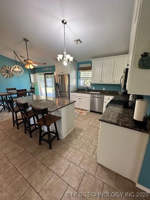 kitchen featuring ceiling fan with notable chandelier, white cabinetry, hanging light fixtures, and appliances with stainless steel finishes