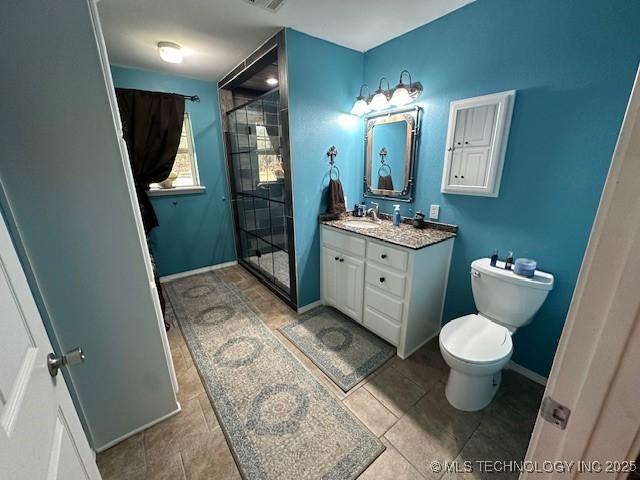 bathroom featuring tile patterned floors, vanity, a shower with shower door, and toilet