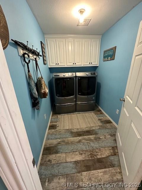 clothes washing area with cabinets and washer and dryer