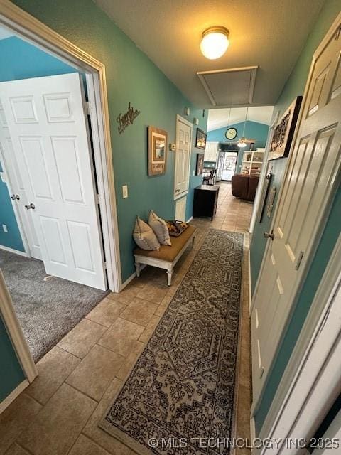 hallway featuring light colored carpet and lofted ceiling