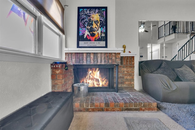 carpeted living room featuring a brick fireplace and ceiling fan