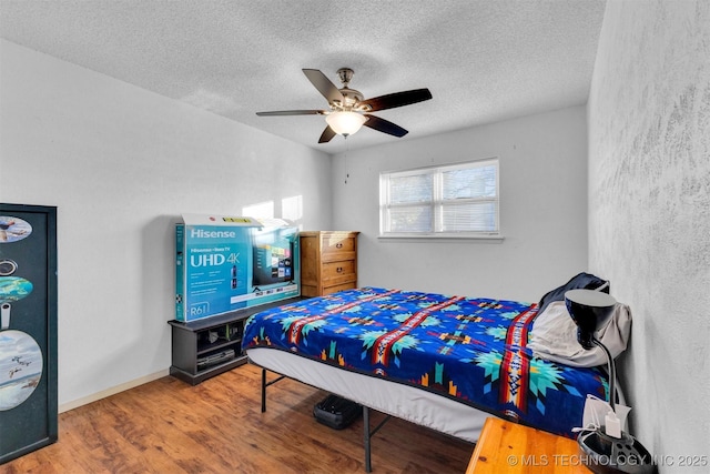 bedroom featuring ceiling fan, a textured ceiling, and hardwood / wood-style flooring