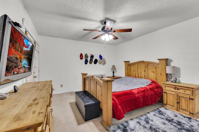 bedroom with ceiling fan, light carpet, and a textured ceiling