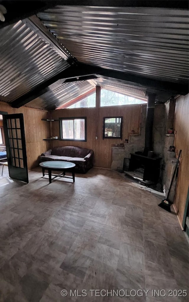 interior space featuring wood walls, a wood stove, and vaulted ceiling