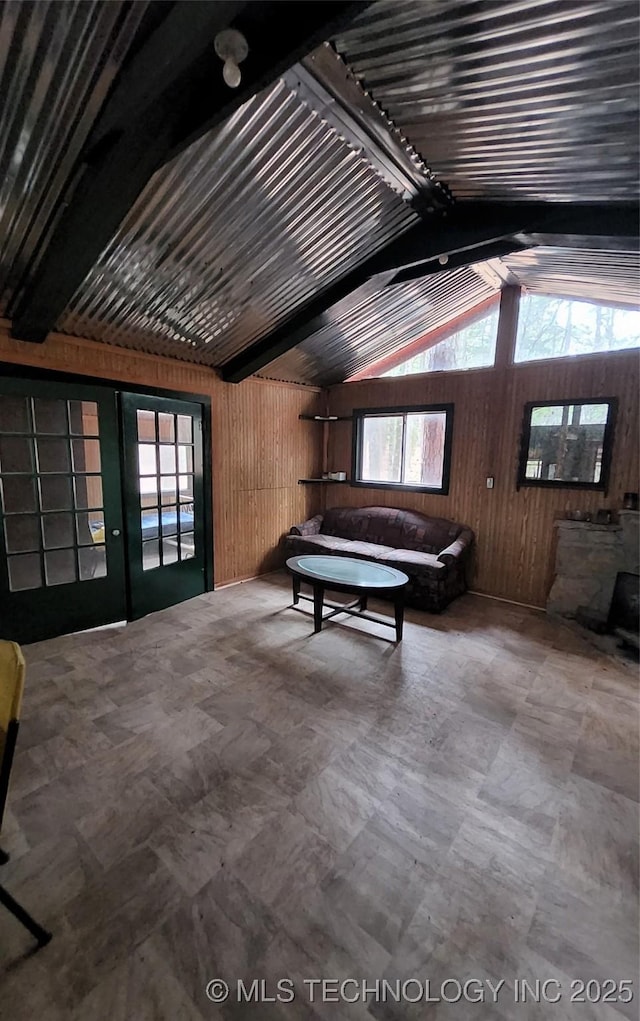 unfurnished living room with lofted ceiling with beams and wood walls