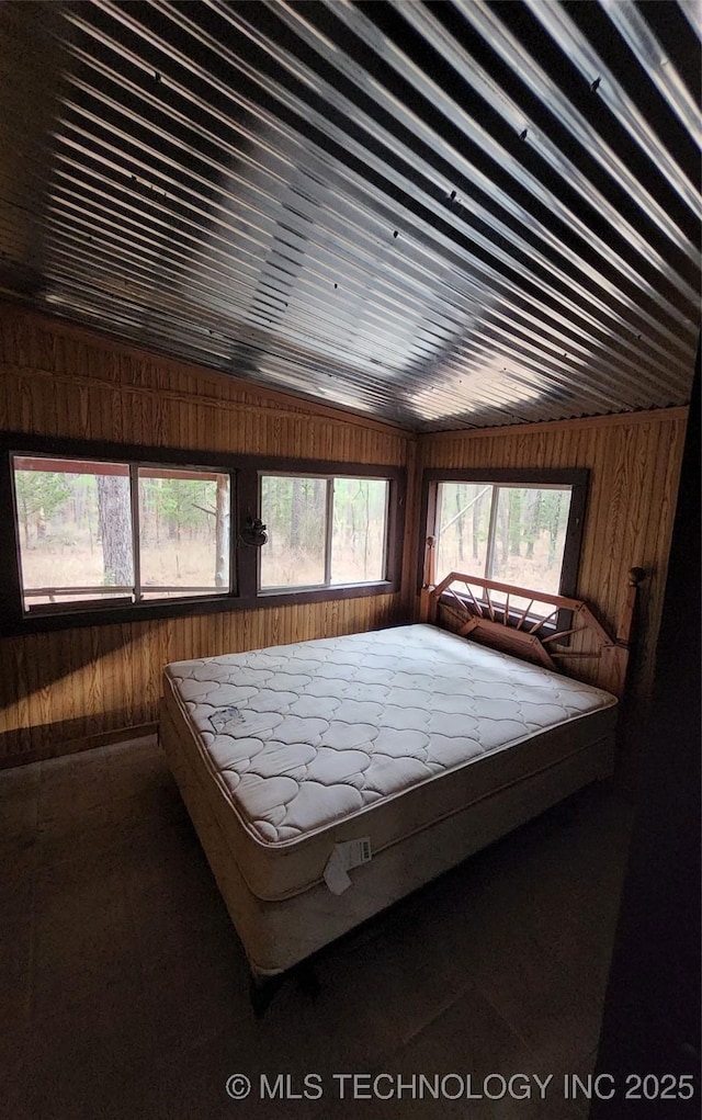 unfurnished bedroom with wooden walls and multiple windows