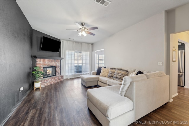 living room with a fireplace, ceiling fan, and dark wood-type flooring