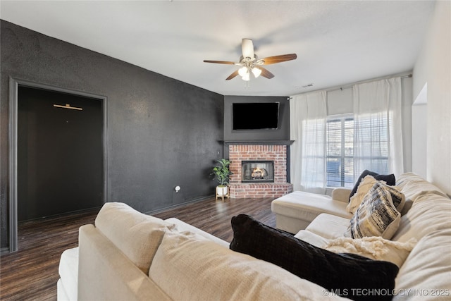 living room featuring ceiling fan, dark wood-type flooring, and a brick fireplace