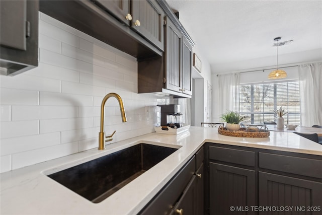 kitchen featuring pendant lighting, tasteful backsplash, dark brown cabinets, and sink