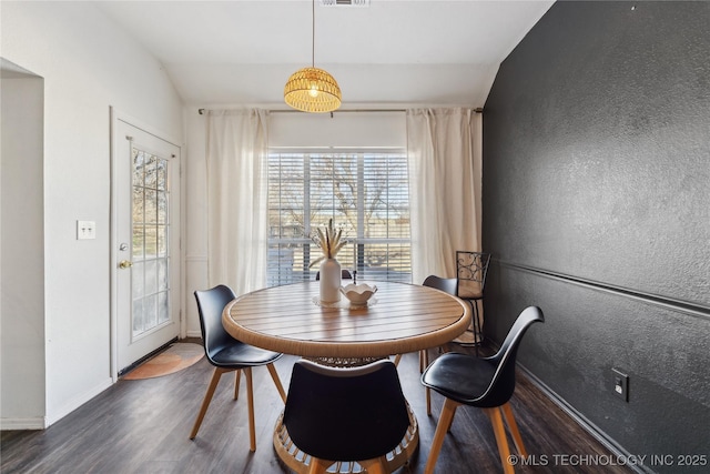 dining area featuring dark wood-type flooring and vaulted ceiling