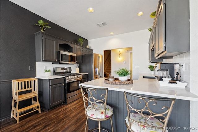 kitchen with sink, stainless steel appliances, tasteful backsplash, dark hardwood / wood-style flooring, and kitchen peninsula