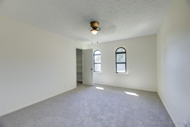 carpeted empty room featuring ceiling fan and a textured ceiling