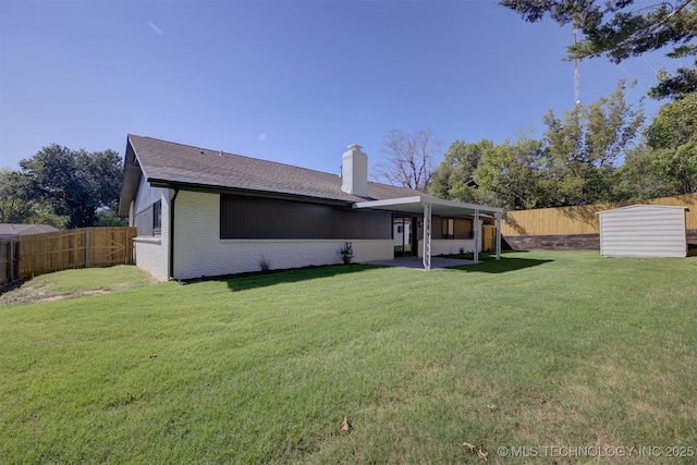 rear view of property with a lawn, a patio, and a storage unit