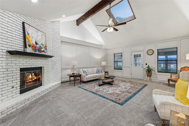 carpeted living room with beam ceiling, a skylight, ceiling fan, high vaulted ceiling, and a fireplace