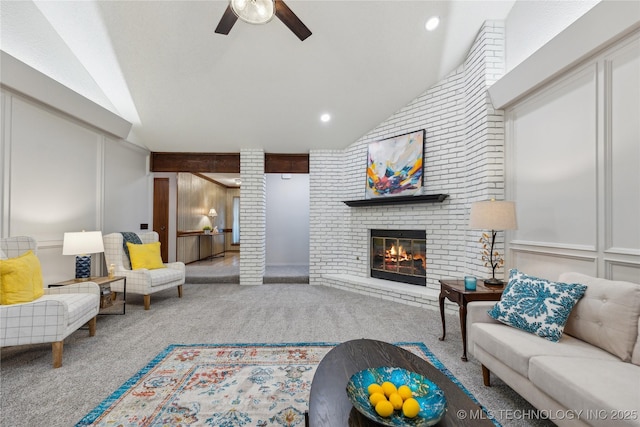 living room with lofted ceiling, a brick fireplace, ceiling fan, carpet floors, and decorative columns