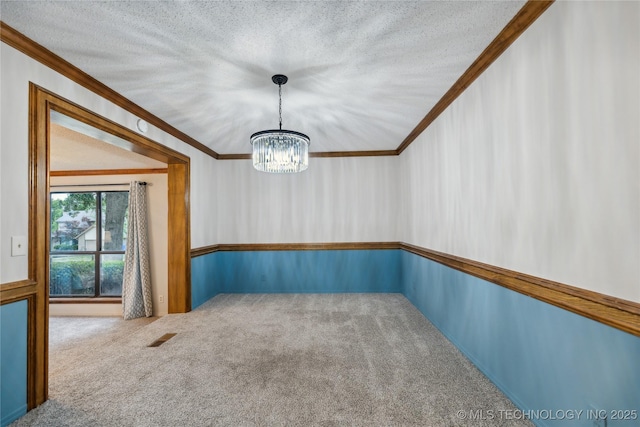 carpeted empty room with crown molding and a chandelier