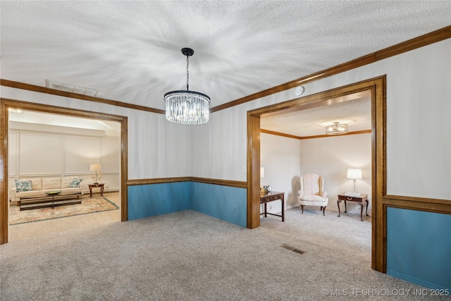 spare room featuring crown molding, carpet, a chandelier, and a textured ceiling