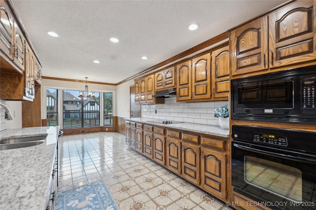 kitchen with decorative backsplash, light stone counters, sink, black appliances, and an inviting chandelier